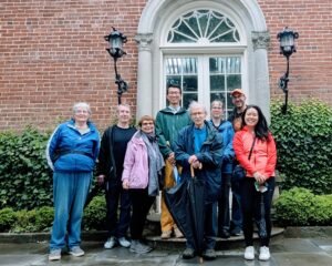 8 poets outdoors at Dumbarton Oaks, in front of a brick building